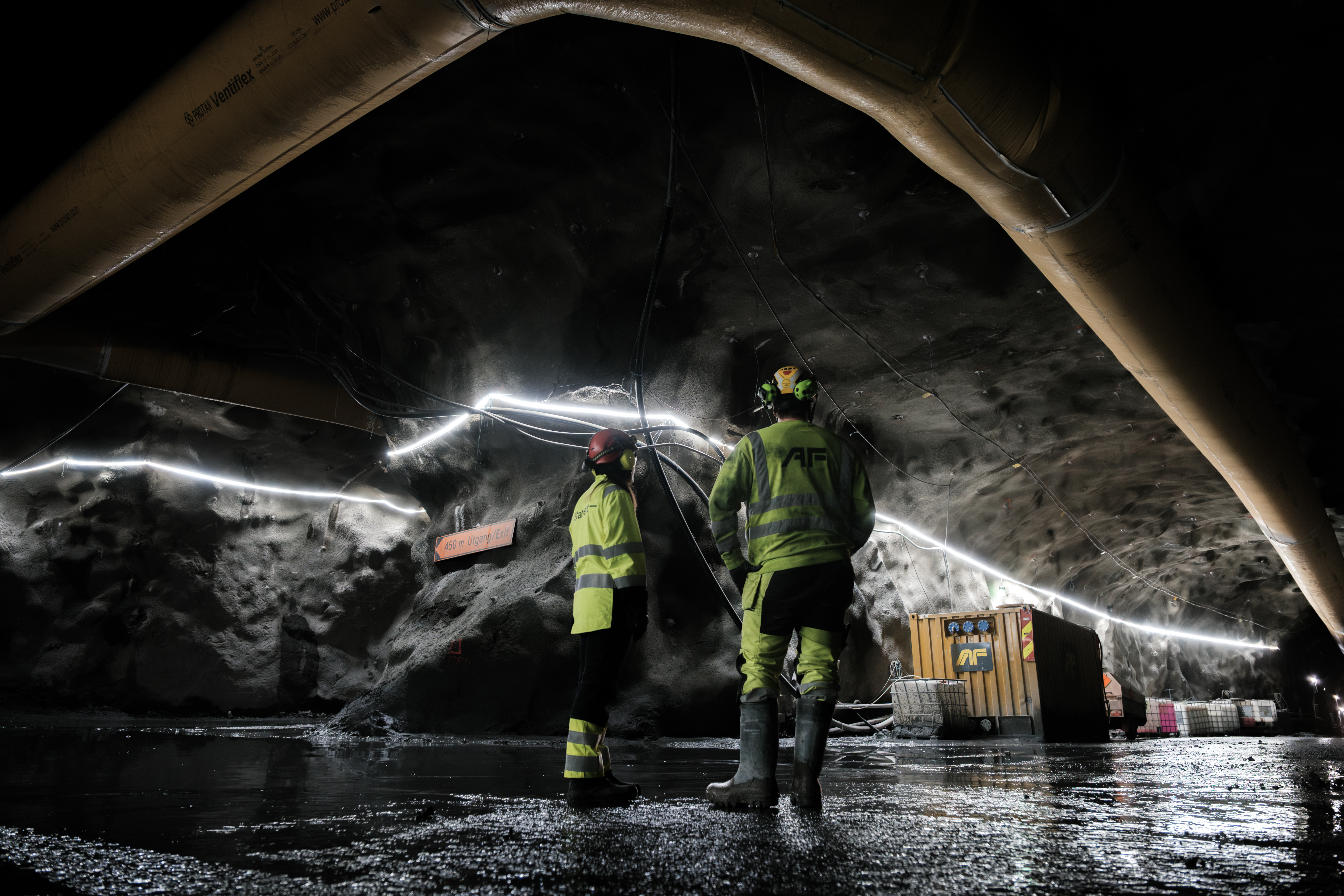 Bilde av to med ryggen til i vernetøy i en tunnel