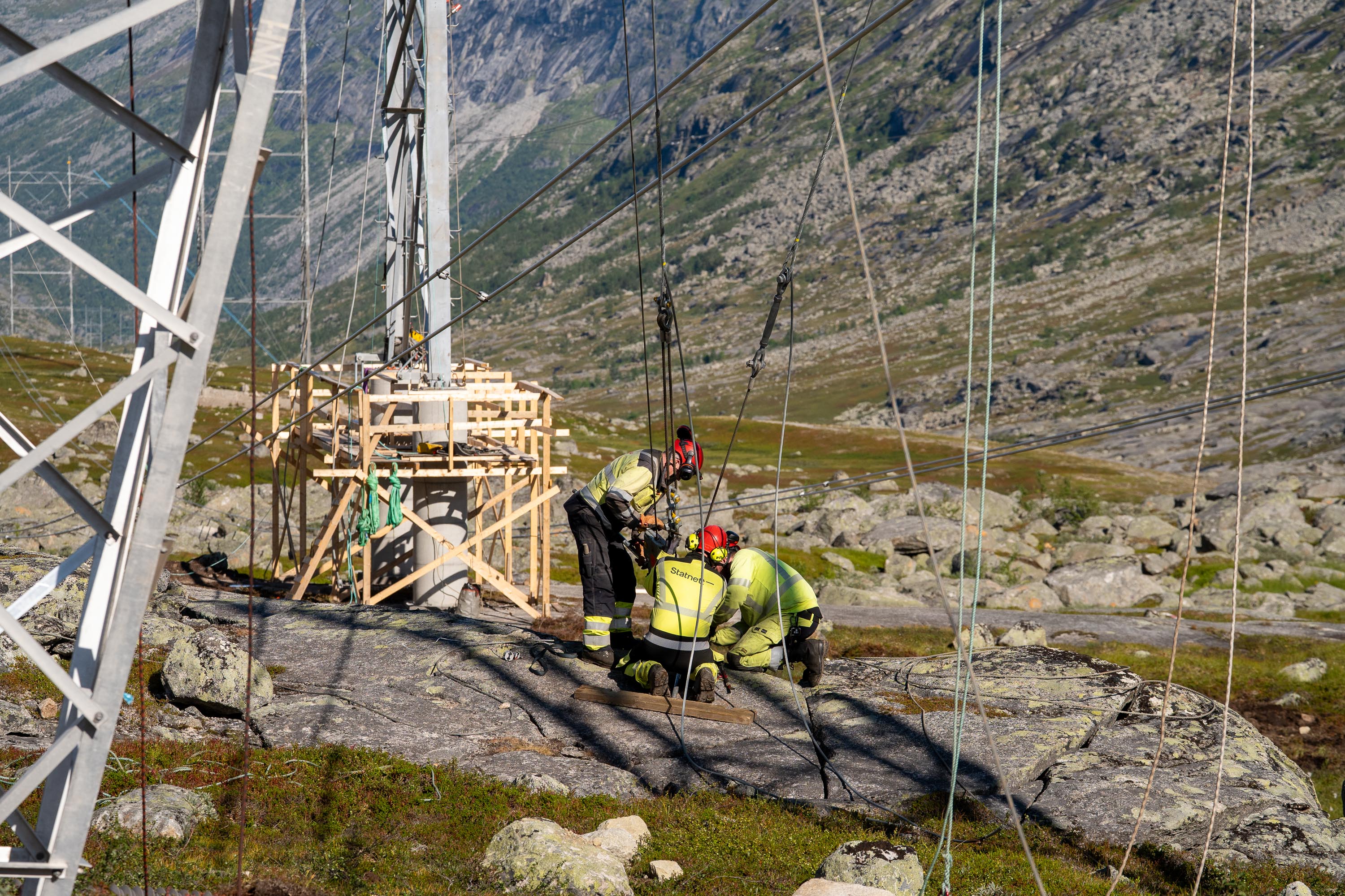 Tre personer som samarbeider på en mast.